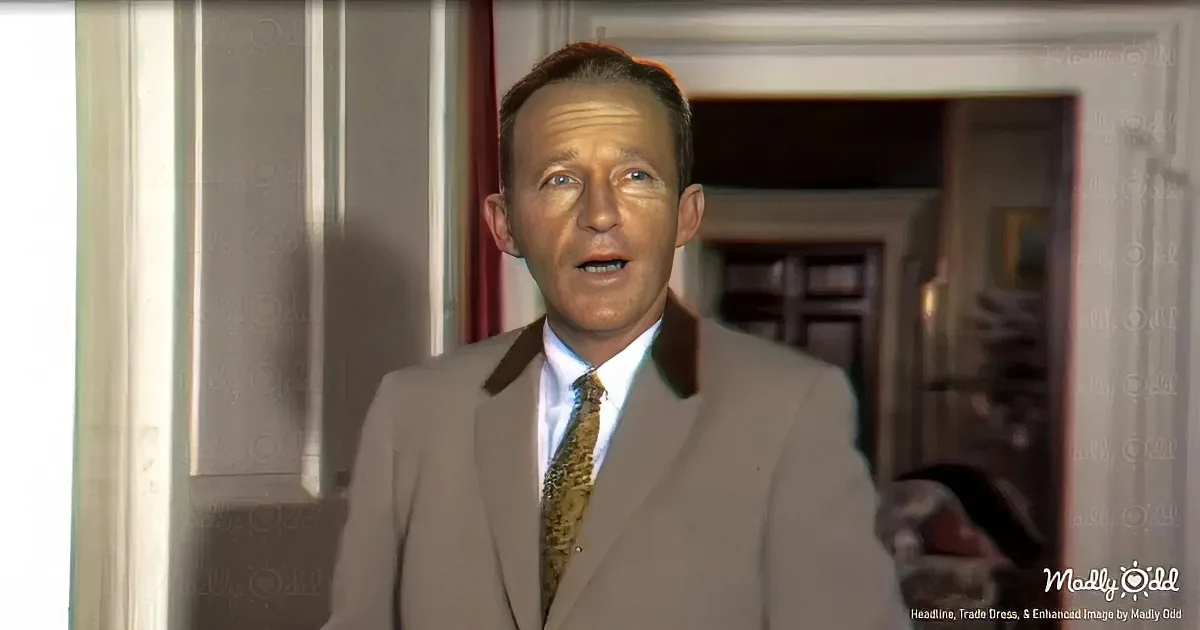 A man in a beige suit and patterned tie stands indoors, looking slightly to the side.