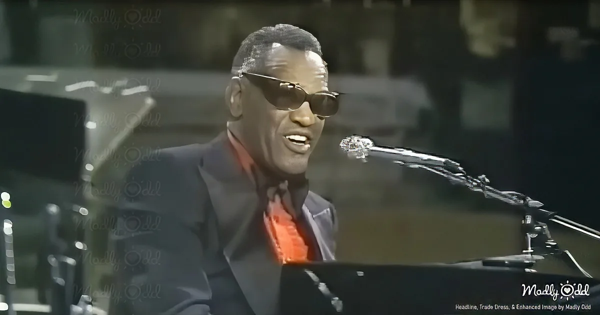 A man in a suit and sunglasses sings into a microphone, wearing a red tie.