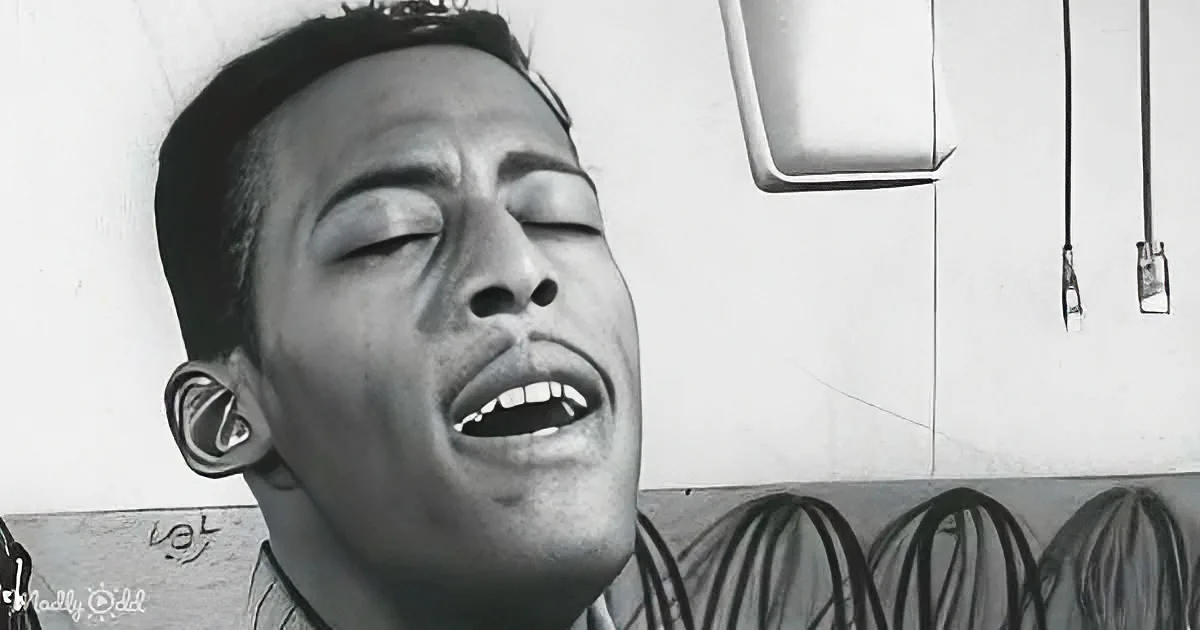 A man with eyes closed, mouth open, and a tattoo on his ear is depicted in a black and white image.