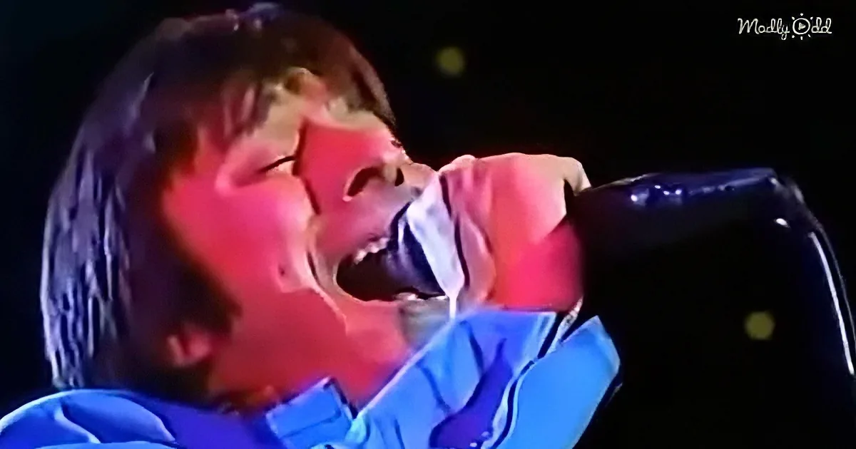 A person in a blue shirt is passionately singing into a microphone.