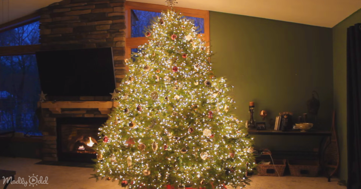 A beautifully decorated Christmas tree with lights and ornaments stands in front of a fireplace in a cozy living room.