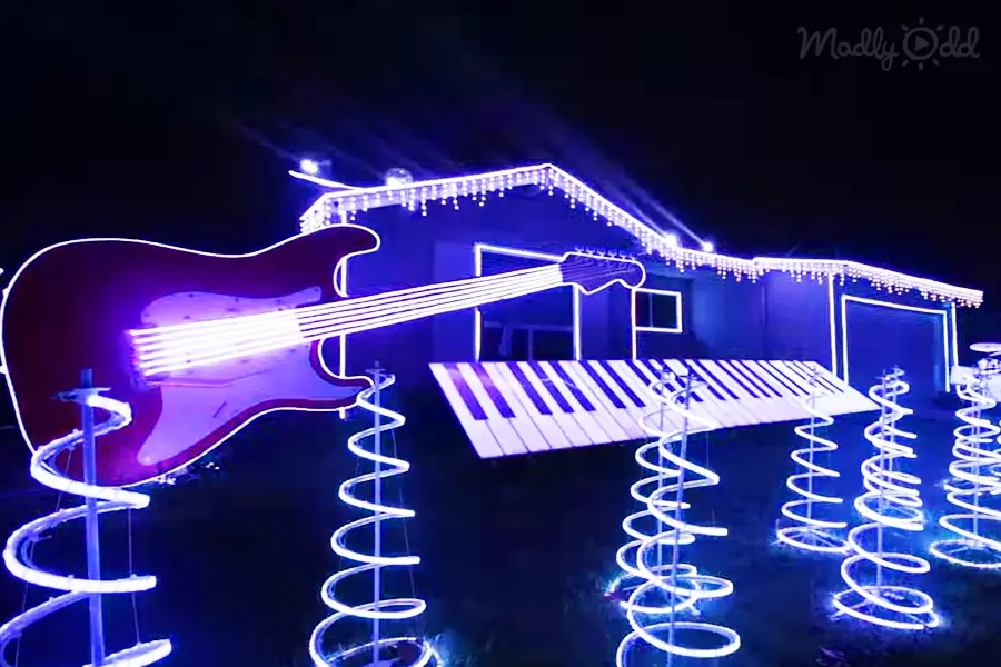 A house is creatively illuminated with neon lights shaped like a guitar and piano, creating a musical theme.