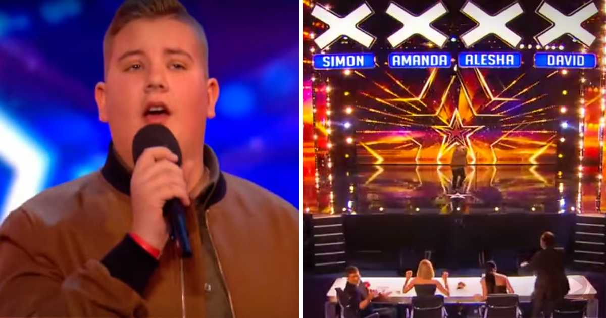 A man sings into a microphone on a stage with judges' names displayed above.