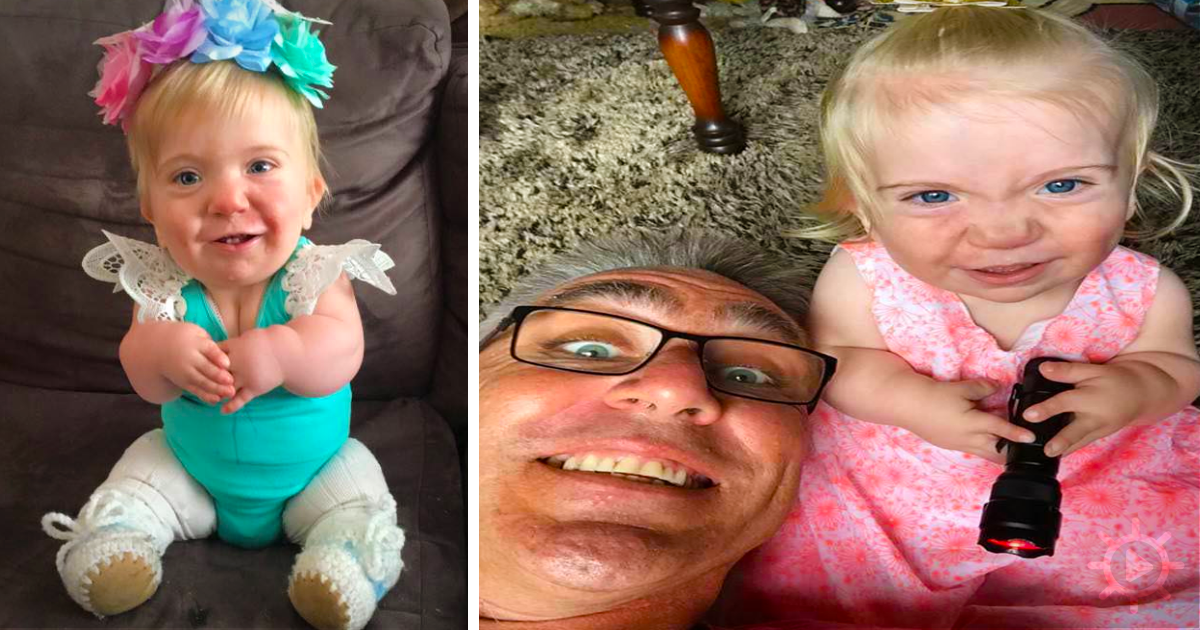 A baby in a teal outfit with a flower headband sits on a couch, smiling, while another baby in a pink dress holds a...