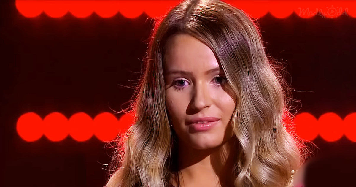 A person with long, wavy blonde hair is seen against a red-lit background.