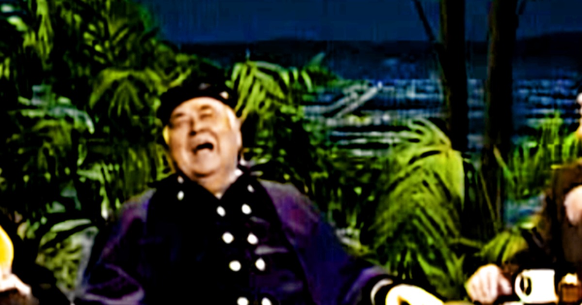 Jonathan Winters in a purple uniform laughs heartily, with Robin Williams in the background, creating a humorous scene.