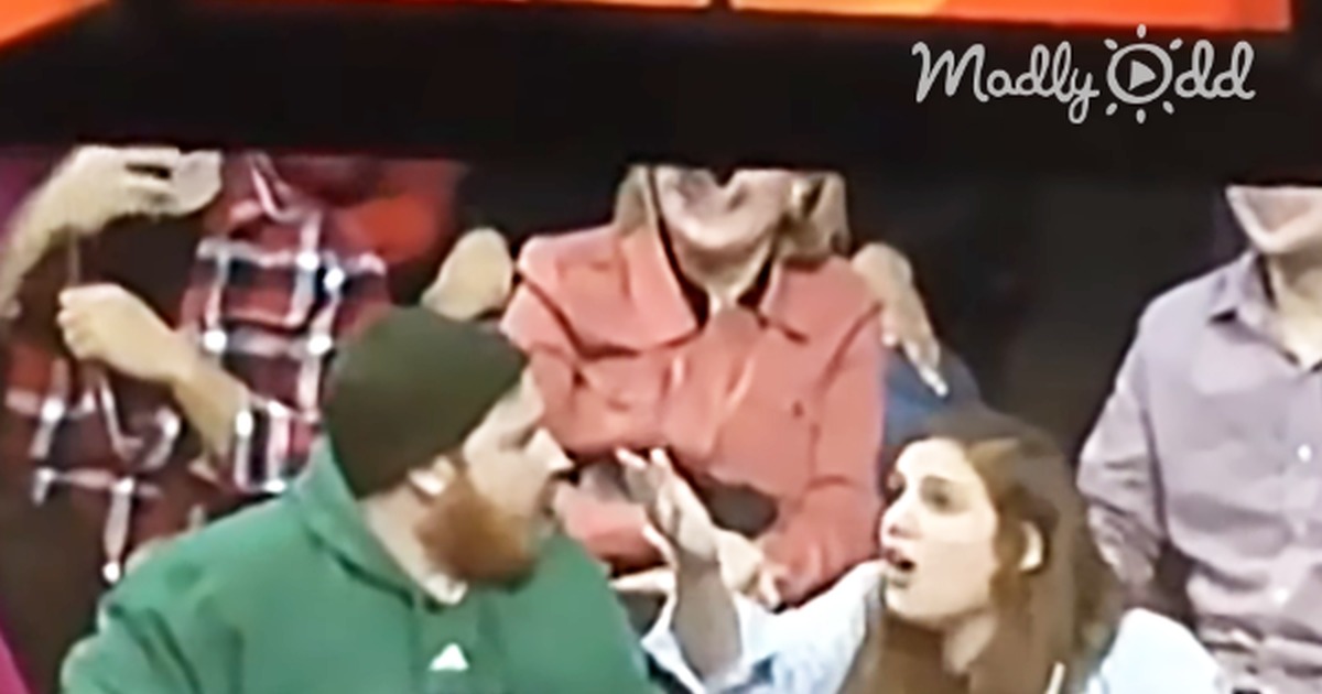 A man in a green hoodie refuses to kiss his girlfriend on the kiss cam, prompting the mascot to whisk her away.