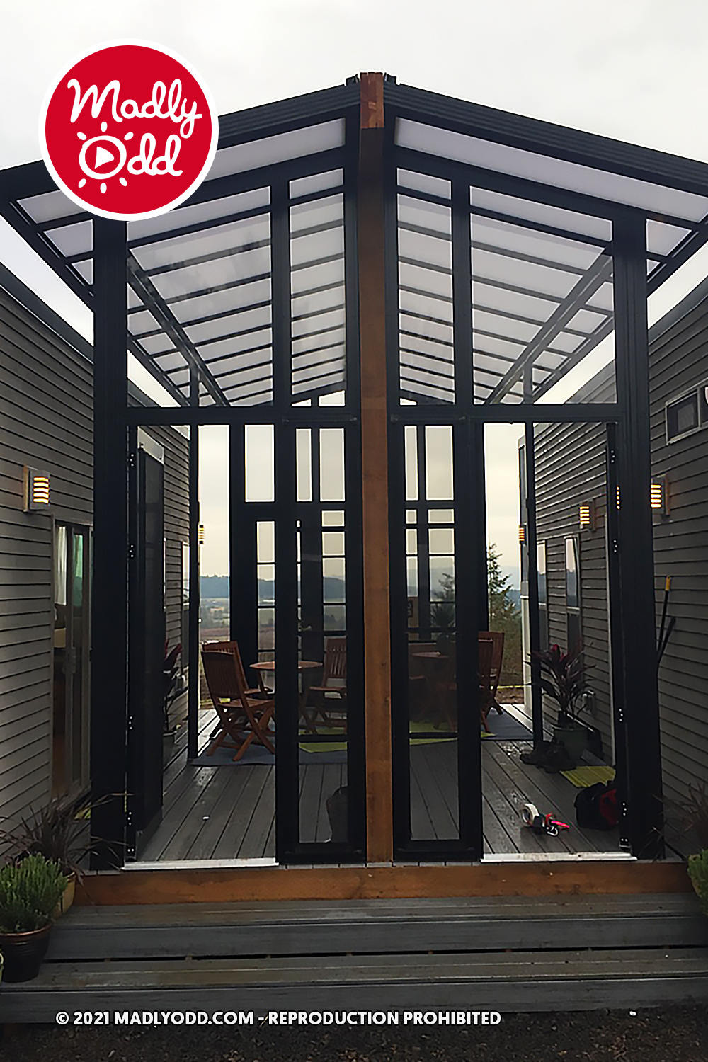 A modern house with a large glass door leading to a deck with outdoor furniture and a scenic view.