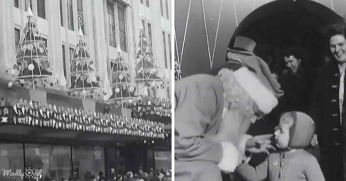 A man in a Santa hat interacts with a child, while a festive Christmas tree display adorns a building.